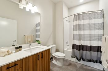 A bathroom with a white sink, a white toilet, and a shower with a black and white striped shower curtain. at Ion Town Center, WA